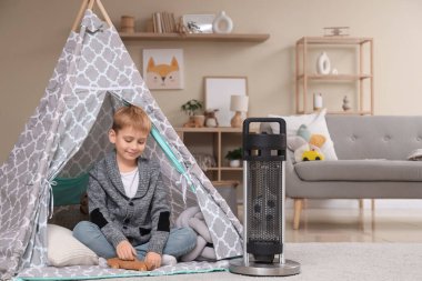 Evdeki elektrikli ısıtıcının yanında küçük şirin bir çocuk oyun çadırında.