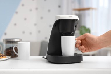 Ofisteki kahve makinesinden fincanı alan kadın, yakın plan.