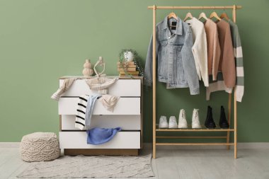 Klozet dağınık giysiler ve oturma odasındaki yeşil duvarın yanında askılar.