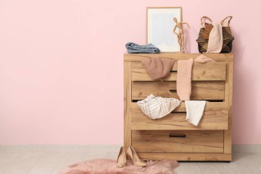 Tuvalet, oturma odasındaki pembe duvarın yanında dağınık giysilerle.