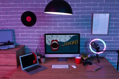Podcaster 'ın iş yeri karanlık stüdyoda bilgisayar ve dizüstü bilgisayarla