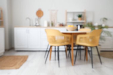 Tezgahlı, raflı ve yemek masalı aydınlık mutfağın bulanık görüntüsü