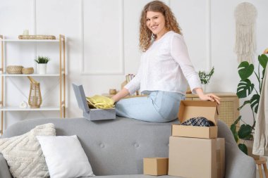 Evde paket kutularını açan genç bir kadın.