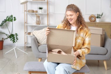 Genç bir kadın evinde yeni topuklularla paket kutusunu açıyor.