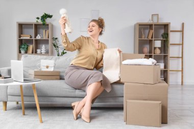 Genç bir kadın yeni şapka ve eşarpla paket kutusunu açıyor.