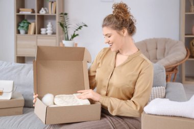 Genç bir kadın yeni kış aksesuarlarıyla birlikte paket kutusunu açıyor.