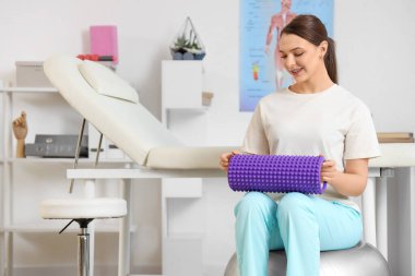 Rehabilitasyon merkezinde köpük silindirli kadın fizyoterapist.