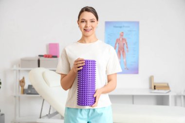 Rehabilitasyon merkezinde köpük silindirli kadın fizyoterapist.