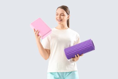 Köpük silindirli kadın fizyoterapist ve arka planda yoga bloğu