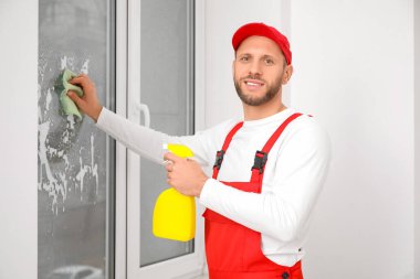 Erkek işçi odada cam yıkıyor.