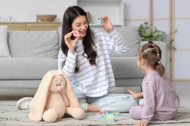 Genç anne ve küçük kızı evde yapı taşlarıyla oynuyorlar.