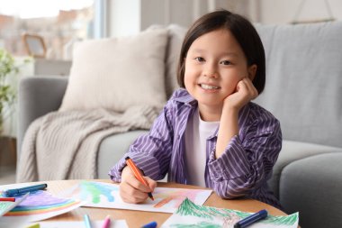 Evdeki masada güzel bir Asyalı kız çiziyor.