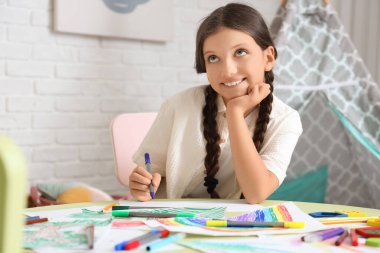 Evdeki masada güzel bir kız resmi çiziyor.