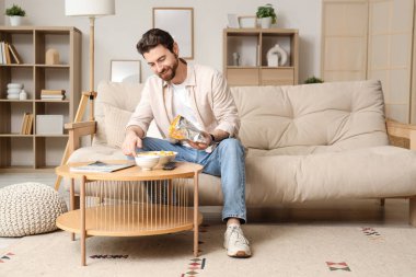 Adam evde TV izlerken lezzetli nacho yiyor.