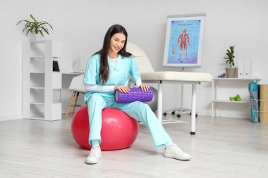 Rehabilitasyon merkezinde köpük silindirli kadın fizyoterapist.