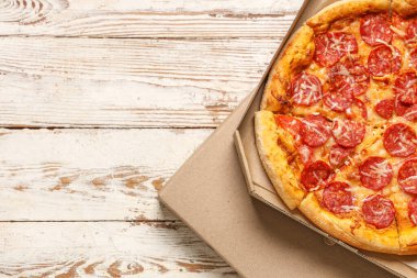 Beyaz ahşap zemin üzerinde lezzetli pizzalar olan karton kutular.