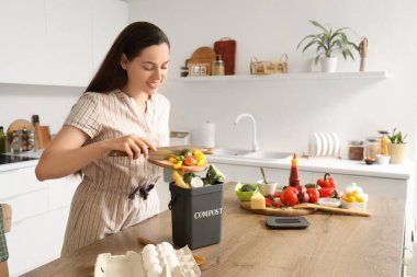 Mutfaktaki gübre için konteynıra yiyecek atan genç bir kadın.