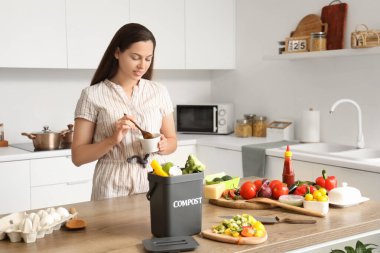 Mutfaktaki masada gübre için yiyecek ve kap taşıyan genç bir kadın.