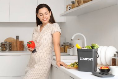 Mutfakta gübre için biber ve kabı olan genç bir kadın.