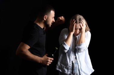 Sarhoş bir adam karanlık arka planda karısını dövüyor. Aile içi şiddet kavramı