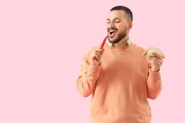 Pembe arka planda lezzetli taco ve biberli genç adam.
