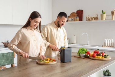 Mutfakta yemek pişirirken gübre kutusu ve sebze artıklarıyla genç bir çift.