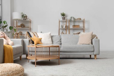 Masalı gri koltuklar, raf üniteleri ve ışık duvarının yanındaki boş poster.