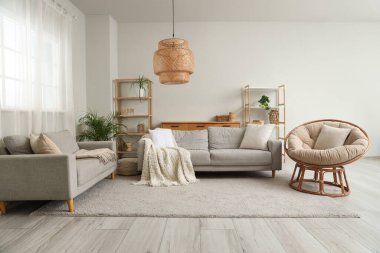 Şık oturma odasının içinde rahat koltuklar, gri koltuklar ve hasır lambalar.