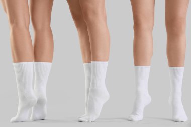 Gri arka planda şık beyaz çoraplı genç kadınların bacakları
