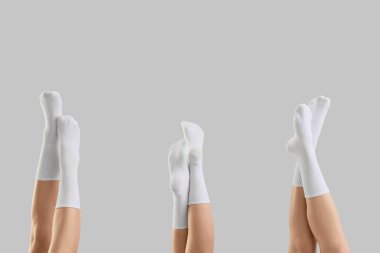 Gri arka planda beyaz çoraplı genç kadınların bacakları