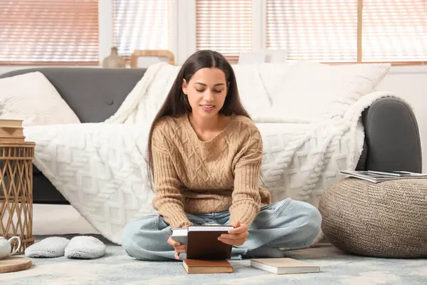 Kitapları evde yerde oturan güzel, genç, mutlu bir kadın.