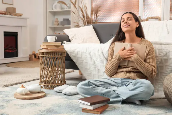 Kitapları evde yerde oturan güzel, genç, mutlu bir kadın.