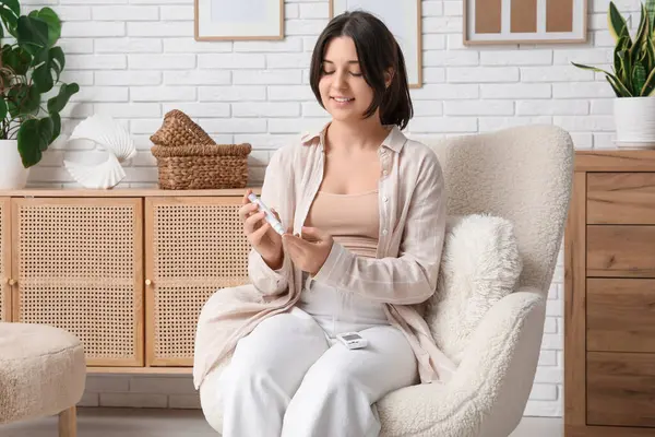 Şeker hastası genç bir kadın evdeki koltukta tükenmez kalem kullanıyor.