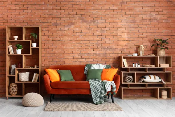 Kırmızı kanepe ve raf üniteleri üzerinde şık yastıklar olan oturma odasının içinde.