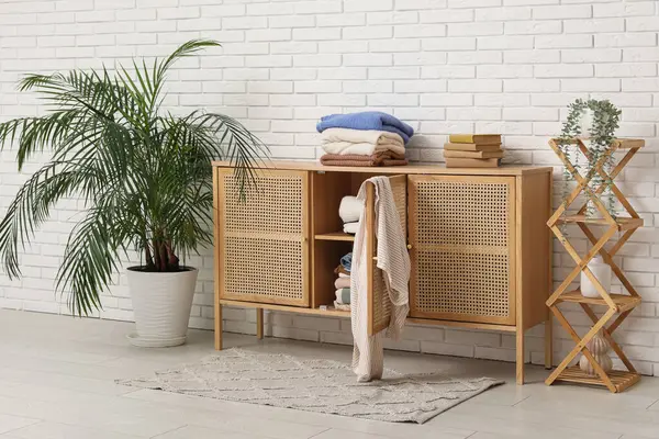 Oturma odasının içinde raflar ve katlanmış giysiler beyaz tuğla duvarın yanında.