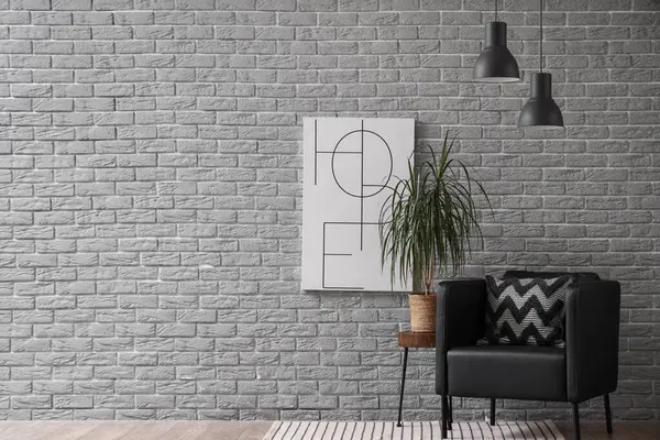 Oturma odasının içinde siyah koltuk, palmiye ağacı ve resim var.