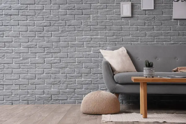 Gri kanepe, masa ve puf ile oturma odasının içinde.