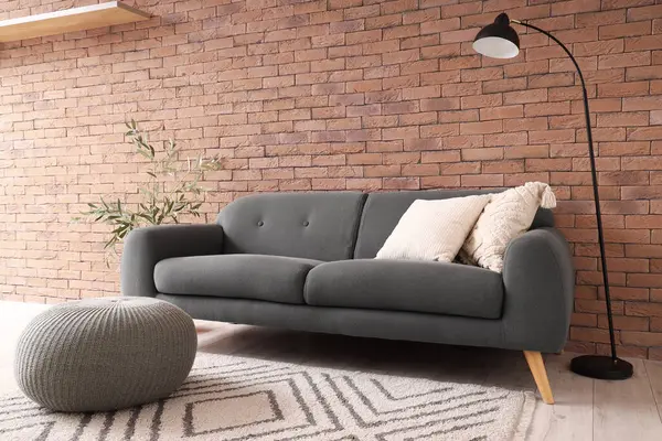 Oturma odasının içinde siyah kanepe, lamba ve puf