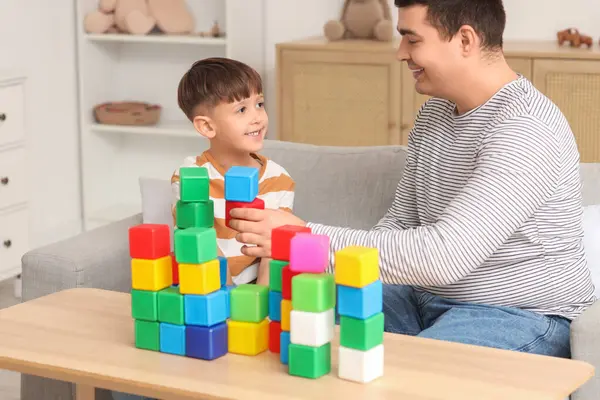 Mutlu baba ve küçük oğlu evdeki masada küplerle oynuyorlar.