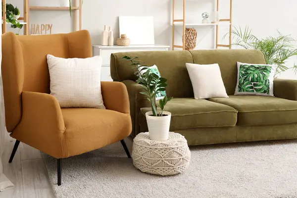 Rahat kahverengi koltuğu, yeşil kanepesi ve çiçekleri olan şık bir oturma odası.