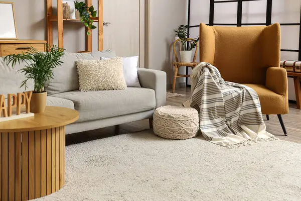 Rahat kahverengi koltuğu, gri kanepesi ve ahşap sehpası olan şık bir oturma odası.