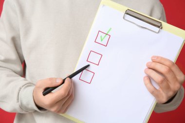 Kırmızı arka planda boş listeli adam, yakın plan. Anket konsepti