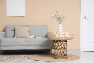 Oturma odasındaki rahat kanepenin yanındaki sehpanın üzerinde çingene çiçekleri olan vazo.