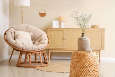 Vazodaki çikila çiçekleri, oturma odasındaki koltuk ve çekmeceler.