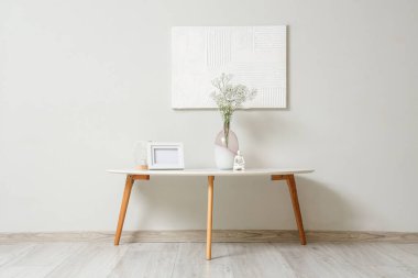 Dekorlu kahve masası ve vazoda gri duvarın yanında vazo çiçekleri.