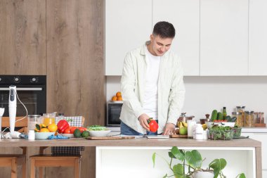 Taze sebzeli, meyveli, vitaminli ve terazili yakışıklı genç adam. Sağlıklı gıda konsepti