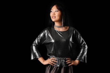 Siyah arka planda gümüş bluzlu güzel bir Asyalı kadın.