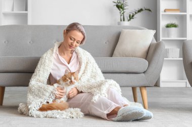 Pijamalı, terlikli ve evde yerde oturan güzel bir kadın.