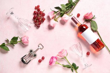Üzümlerden yapılmış çerçeve, bardaklar, pembe şarap şişesi ve açık arkaplanda güzel güller.