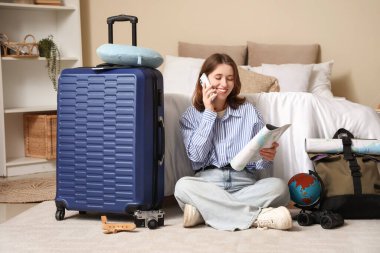 Yatak odasında cep telefonuyla konuşan haritalı bir bayan gezgin. Güzergah kavramı